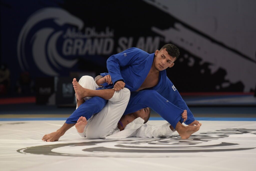 Dois atletas de jiu-jitsu, com quimonos azul e branco, durante uma luta.